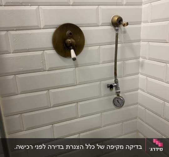 ברז ומד לחץ על קיר אריחים לבנים בחדר אמבטיה